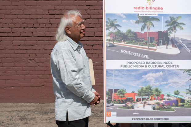 During a Sept. 19 press conference, Radio Bilingüe Co-Founder and Co-Executive Director Hugo Morales listens to a speaker. Plans to make the Central Valley Cheese building a center for Radio Bilingüe are at right. Photo by Peter Maiden