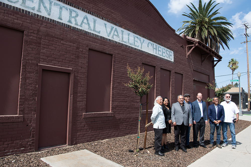 Speakers at a press conference held by Radio Bilingüe and Producers Dairy pose in front of the building Producers Dairy is making available to the radio station. (L to R) Hugo Morales of Radio Bilingüe, María Reina Lemus of Assembly Member Joaquin Arambula’s Office, José Martínez-Saldaña and José Moran of Radio Bilingüe, Producers Dairy CEO Scott Shehadey, Fresno City Council Member Miguel Arias and Radio Bilingüe News Director Samuel Orozco. Photo by Peter Maiden