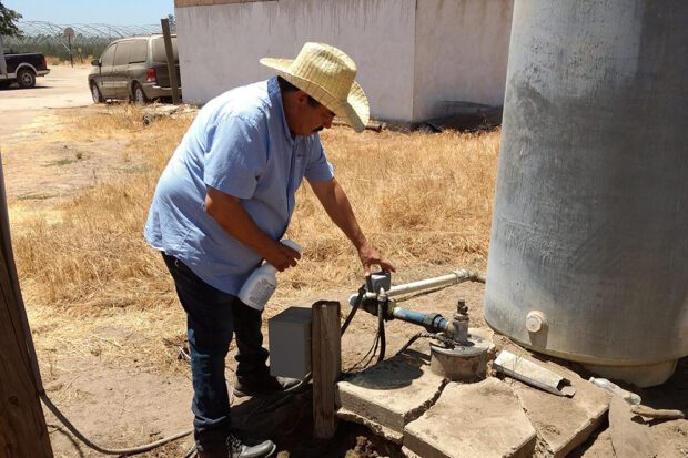 Cristobal Chavez checks the water system on his family's Tulare County farm. Photo by Vic Bedoian