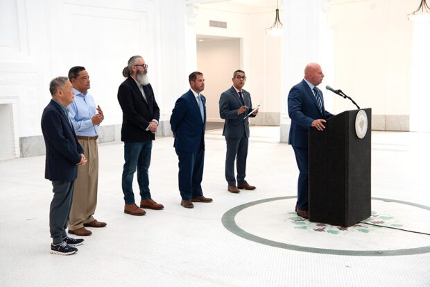 Speaking to the TV cameras in the Hotel Fresno lobby are, right to left, Fresno Mayor Jerry Dyer, City Council Member Miguel Arias, Assembly Member Joaquin Arambula, planner Jason Hatwig, and developers Refebe Gouges and Eugene Kim. Photo by Peter Maiden