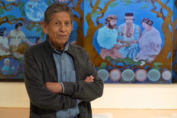 John Sierra at Arte Américas with a small version of a mural he painted on a wall in Sacramento. Photo by Peter Maiden