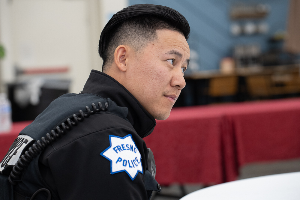 Hmong Fresno Police Patrol Officer C. Yang listened to a speaker.