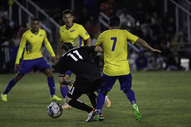 Fuego FC’s Raul Velador Mendiola mixes it up with Farolito’s Herlbert Soto as two of Soto’s teammates look on. Photo by Peter Maiden