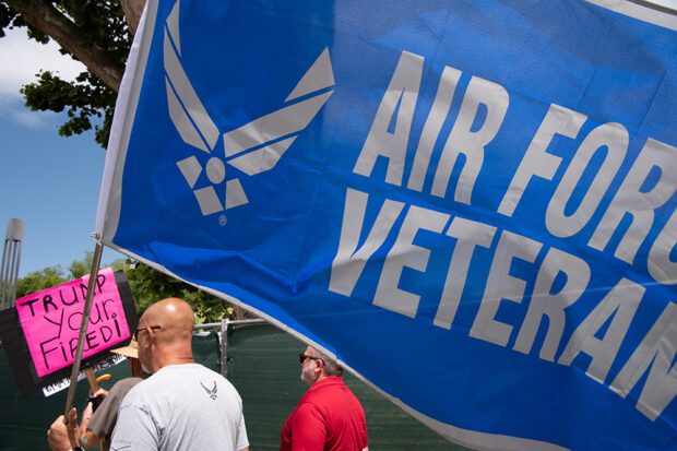 On May 17, an Air Force veteran marches with a flag in protest against the Trump administration cutting benefits to veterans. Photo by Peter Maiden